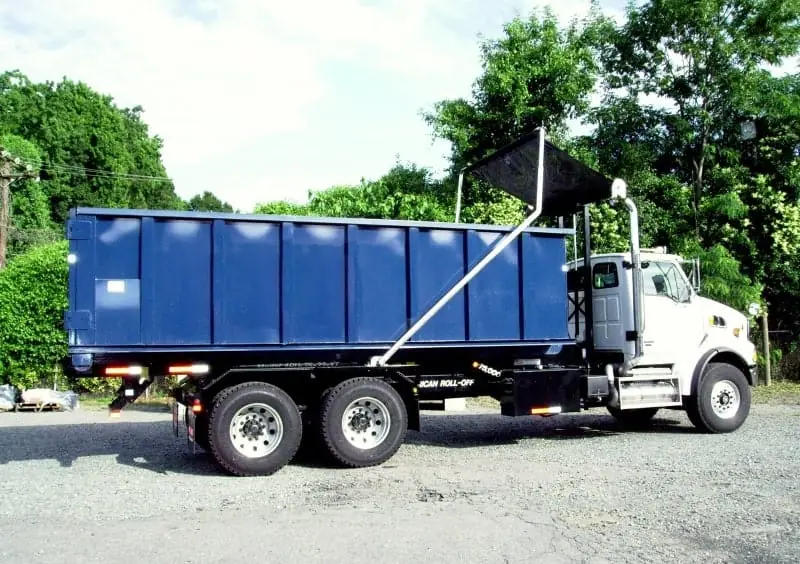 Roll-off truck carrying a blue container with a tarp arm